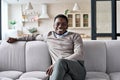 Young happy adult black man sitting on sofa at home looking at camera. Royalty Free Stock Photo