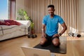 Young happy African American black male exercising at home doing an online workout class on a yoga mat in his living Royalty Free Stock Photo