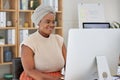 Young happy african american businesswoman smiling while working on a desktop computer while sitting in an office at Royalty Free Stock Photo