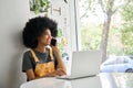 Young happy African American student speaking on phone using laptop in cafe. Royalty Free Stock Photo