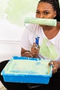 Funny happy african american woman painting interior wall with paint roller in new house, close-up. A woman with roller Royalty Free Stock Photo