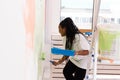 Young happy african american woman painting interior wall with paint roller in new house. A woman with roller applying Royalty Free Stock Photo