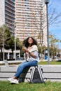 Young happy African American woman sitting in city park using cell phone. Royalty Free Stock Photo