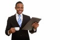 Young happy African businessman smiling while holding clipboard Royalty Free Stock Photo