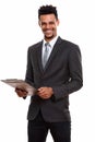 Young happy African businessman smiling while holding clipboard Royalty Free Stock Photo
