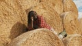 Young happy african farmer lying on the stack of hay rolls and resting Royalty Free Stock Photo