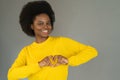 Young happy African girl in yellow sweater showing heart sign with fingers, feels grateful for love. Royalty Free Stock Photo