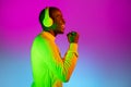 Young happy African handsome man with headphones isolated over gradient magenta yellow neon background.