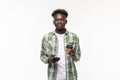 Young happy African man smiling while talking on mobile phone and holding coffee cup against white background Royalty Free Stock Photo