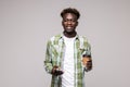 Young happy African man smiling while talking on mobile phone and holding coffee cup against white background Royalty Free Stock Photo