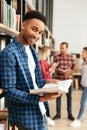 Young happy african man student standing in library reading book Royalty Free Stock Photo