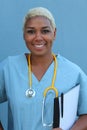 Young happy afro american doctor standing at hospital ward with clipboard and pen in hand. Smiling, looking at camera Royalty Free Stock Photo