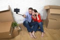 Young happy American couple sitting on floor taking selfie photo celebrating moving in new house or apartment Royalty Free Stock Photo