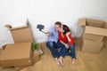 Young happy American couple sitting on floor taking selfie photo celebrating moving in new house or apartment Royalty Free Stock Photo