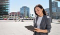 Young happy Asian business woman standing on city street using digital tablet. Royalty Free Stock Photo