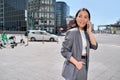 Young happy Asian business woman wears suit talking on the phone on city street. Royalty Free Stock Photo