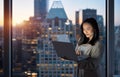 Young happy Asian business woman working on laptop standing at night in office. Royalty Free Stock Photo