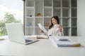 Young happy asian business woman working at office computer desk smiling drinking cup of coffee relaxed Royalty Free Stock Photo