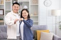 Young happy Asian couple man and woman smiling and looking at camera together, holding keys to their new apartment house Royalty Free Stock Photo