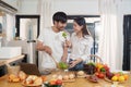 Young happy asian couple preparing healthy meal in kitchen at home. Food and healthy lifestyle concept. Royalty Free Stock Photo