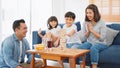 Young happy Asian family play jenga game together at home. Weekend holiday leisure party