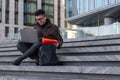 Young happy Asian man student sit on the steps with laptop Royalty Free Stock Photo