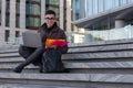 Young happy Asian man student sit on the steps with laptop Royalty Free Stock Photo