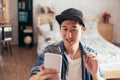 Young happy Asian man talking video call via smartphone wearing headphones at home. Royalty Free Stock Photo