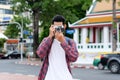 Young happy asian man tourist holding camera, Asian traveler man smiling while holding vintage camera in city urban street on