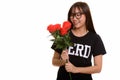 Young happy Asian nerd teenage girl smiling and holding red rose Royalty Free Stock Photo