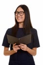 Young happy Asian teenage girl smiling while holding book and th Royalty Free Stock Photo