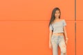 Young beautiful Asian teenage girl against orange wall Royalty Free Stock Photo