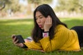 Young happy Asian woman in city park - lifestyle portrait of  cheerful and pretty Korean girl taking selfie with mobile phone Royalty Free Stock Photo