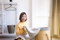 Young happy asian woman doing laundry with basket at home