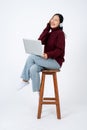 Young happy Asian woman enjoys listening to music through headphones while sitting on a chair Royalty Free Stock Photo