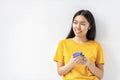 young happy Asian woman holding mobile phone looking away and smiling on white background. Copy space Royalty Free Stock Photo