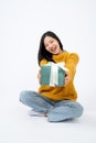 Young happy Asian woman holding a surprise gift box and sitting on a floor on a white background Royalty Free Stock Photo