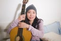 Young happy Asian woman playing guitar in bed - attractive and beautiful Chinese girl in bedroom enjoying singing and writing Royalty Free Stock Photo