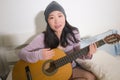 Young happy Asian woman playing guitar in bed - attractive and beautiful Japanese girl in bedroom enjoying singing and writing Royalty Free Stock Photo