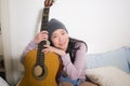 Young happy Asian woman playing guitar in bed - attractive and beautiful Korean girl in bedroom enjoying singing and writing music Royalty Free Stock Photo