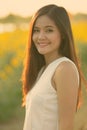 Young happy Asian woman smiling against field of blooming sunflowers Royalty Free Stock Photo