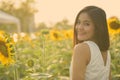 Young happy Asian woman smiling and looking back in the field of blooming sunflowers Royalty Free Stock Photo