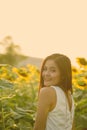 Young happy Asian woman smiling and looking back in the field of blooming sunflowers Royalty Free Stock Photo