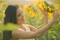 Young happy Asian woman smiling and looking at sunflower in the field of blooming sunflowers Royalty Free Stock Photo