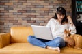 Young Asian woman and Chihuahua puppy sitting togehter on sofa at home Royalty Free Stock Photo