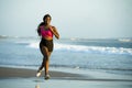 Young happy and attractive African American runner woman exercising on running workout at beautiful beach jogging and enjoying sun Royalty Free Stock Photo