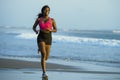 Young happy and attractive African American runner woman exercising on running workout at beautiful beach jogging and enjoying sun Royalty Free Stock Photo