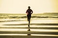 Young happy and attractive African American runner woman exercising on running workout at beautiful beach jogging and enjoying sun Royalty Free Stock Photo