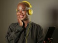 Young happy and attractive afro American woman with yellow headphones and mobile phone listening to internet music song smiling ch Royalty Free Stock Photo