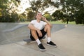 Young happy and attractive American man 30s sitting on skate board after sport boarding training session talking on mobile phone Royalty Free Stock Photo